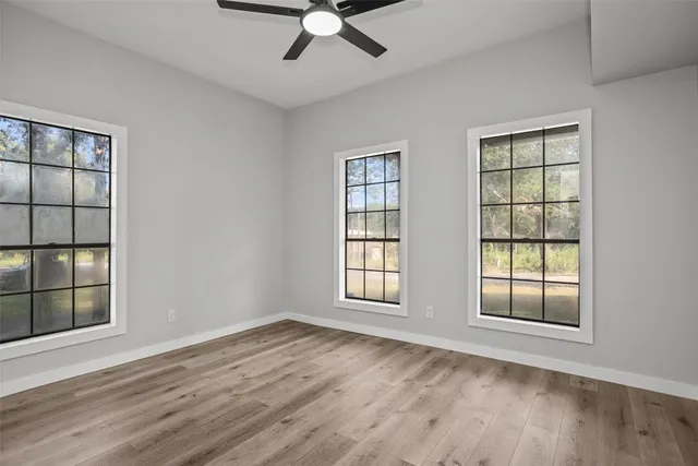 a view of an empty room with a window and wooden floor