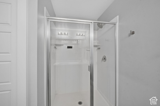 1081 Bowery Way Mapleton, UT 84664 - Photo 26 of 41 Shower enclosure with clear glass panels, chrome hardware, built-in shelving, and a wall-mounted showerhead
