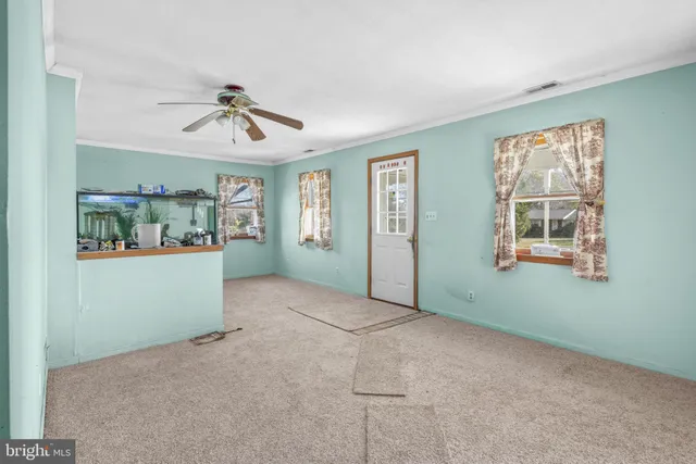 an empty room with windows and fan