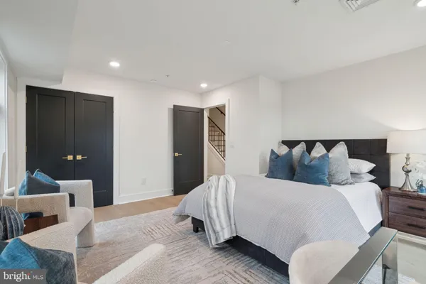 a bedroom with bed a mirror and a large window