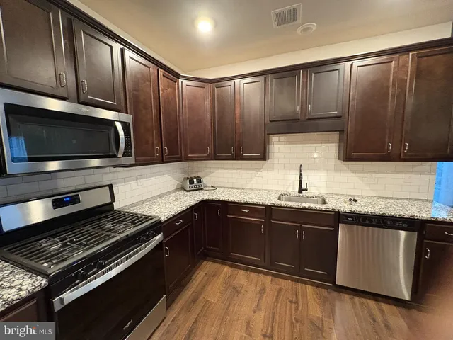 a kitchen with wooden cabinets stove top oven and sink