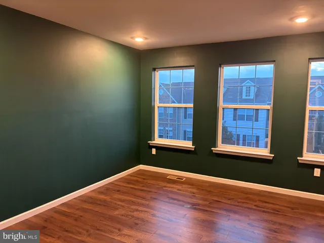 a view of a hallway with wooden floor and a bathroom