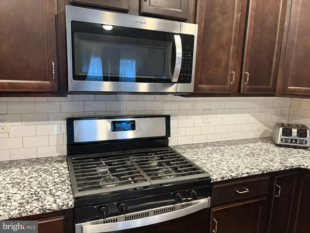 a kitchen with granite countertop a stove and a microwave
