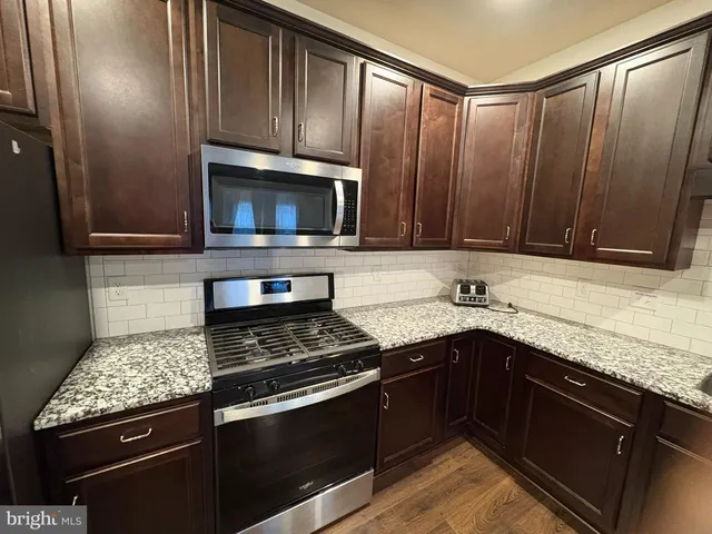 a kitchen with granite countertop wood cabinets stainless steel appliances and a sink