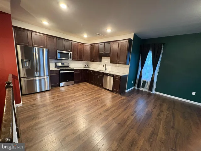 a kitchen with stainless steel appliances kitchen island granite countertop a refrigerator stove and sink