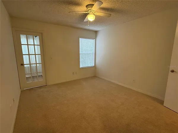 an empty room with windows and fan