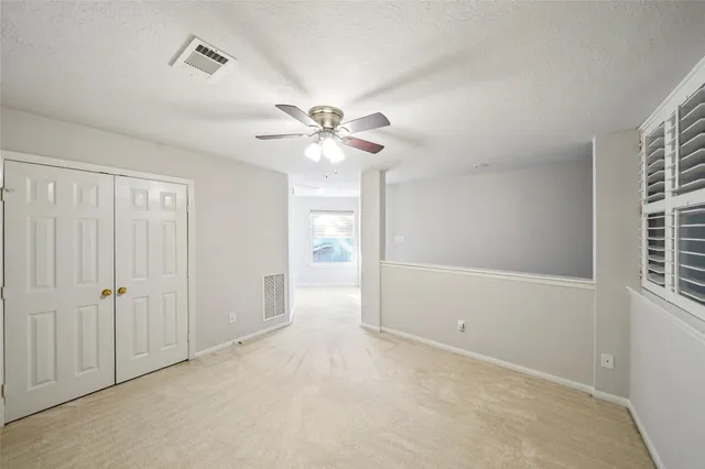 an empty room with windows and fan