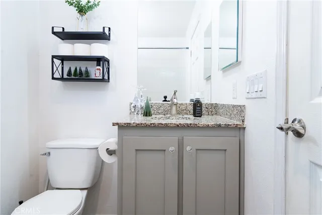 a bathroom with a granite countertop toilet sink and mirror