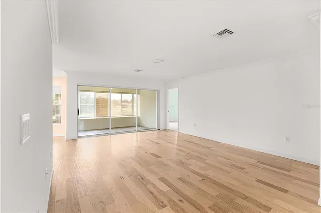 a view of an empty room with wooden floor and window