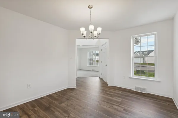 a view of a room with wooden floor chandelier and windows