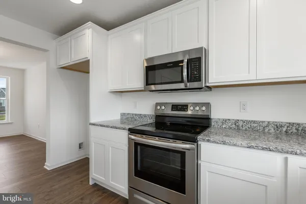 a kitchen with stainless steel appliances granite countertop white cabinets granite counter tops and a wooden floors