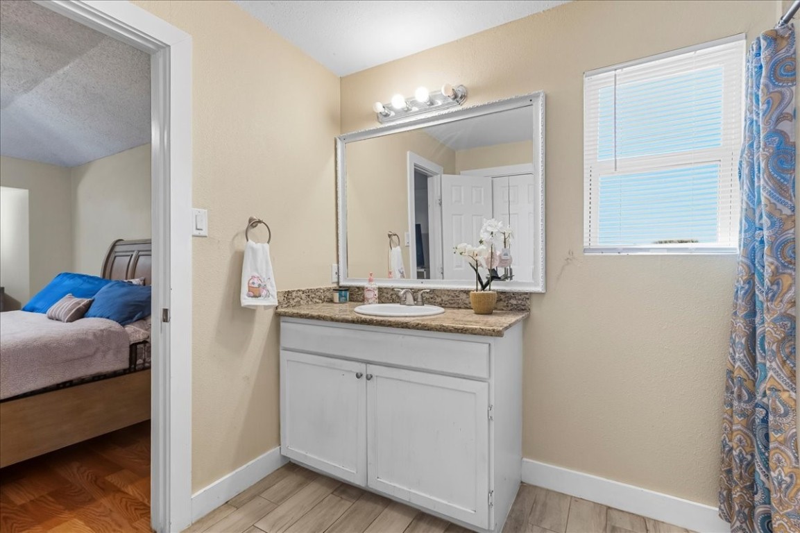 12926 Grovemill Drive Houston, TX 77045 - Photo 17 of 30 a en suite bathroom with a granite countertop sink and a mirror