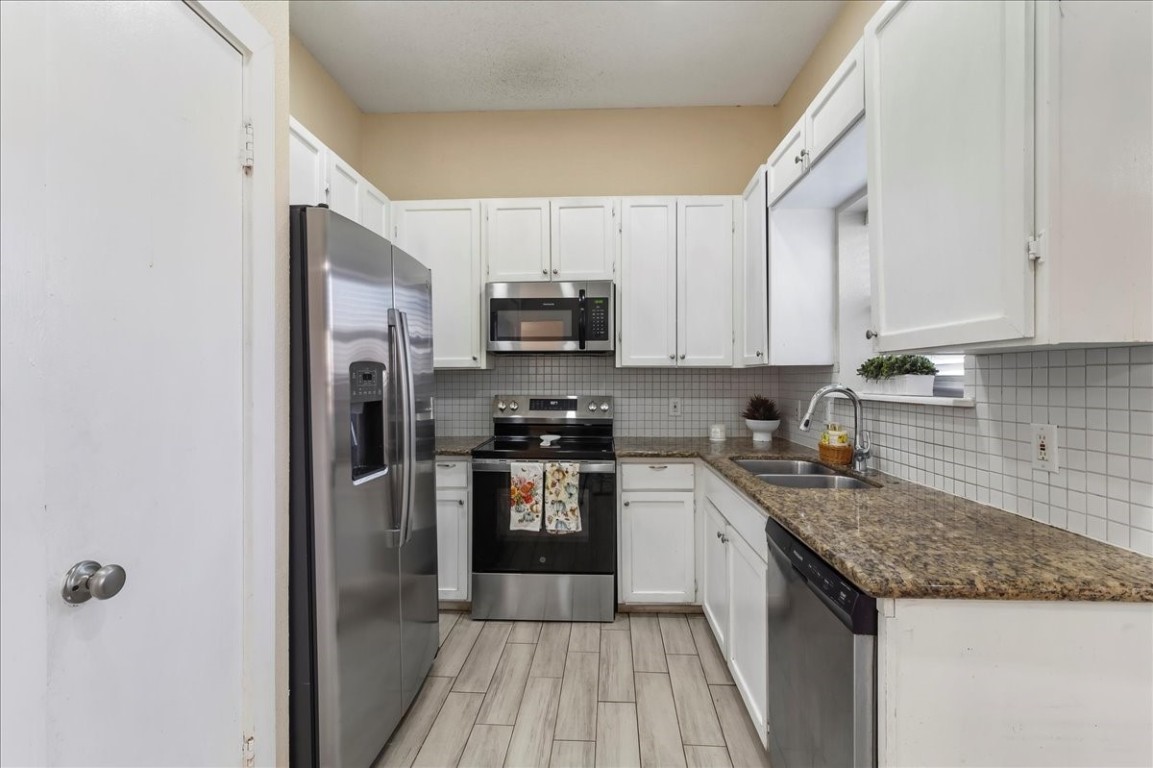12926 Grovemill Drive Houston, TX 77045 - Photo 8 of 30 a kitchen with a sink a stove top oven a refrigerator and cabinets