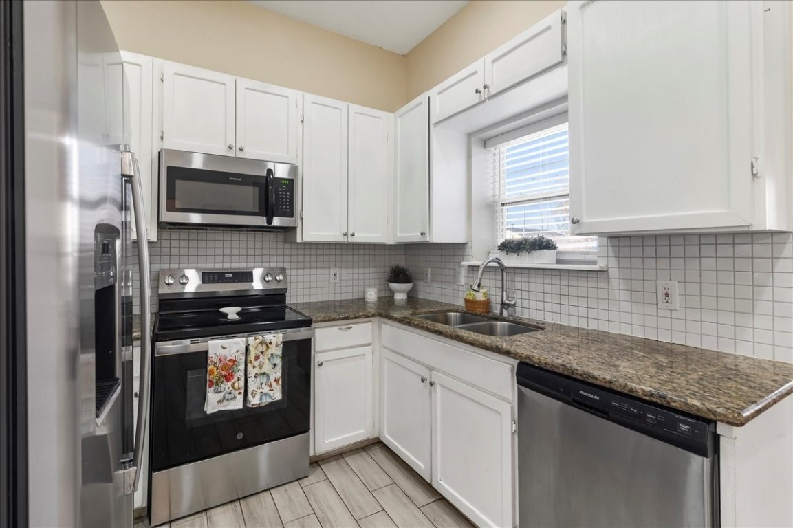 12926 Grovemill Drive Houston, TX 77045 - Photo 9 of 30 a kitchen with stainless steel appliances granite countertop a sink stove microwave and refrigerator
