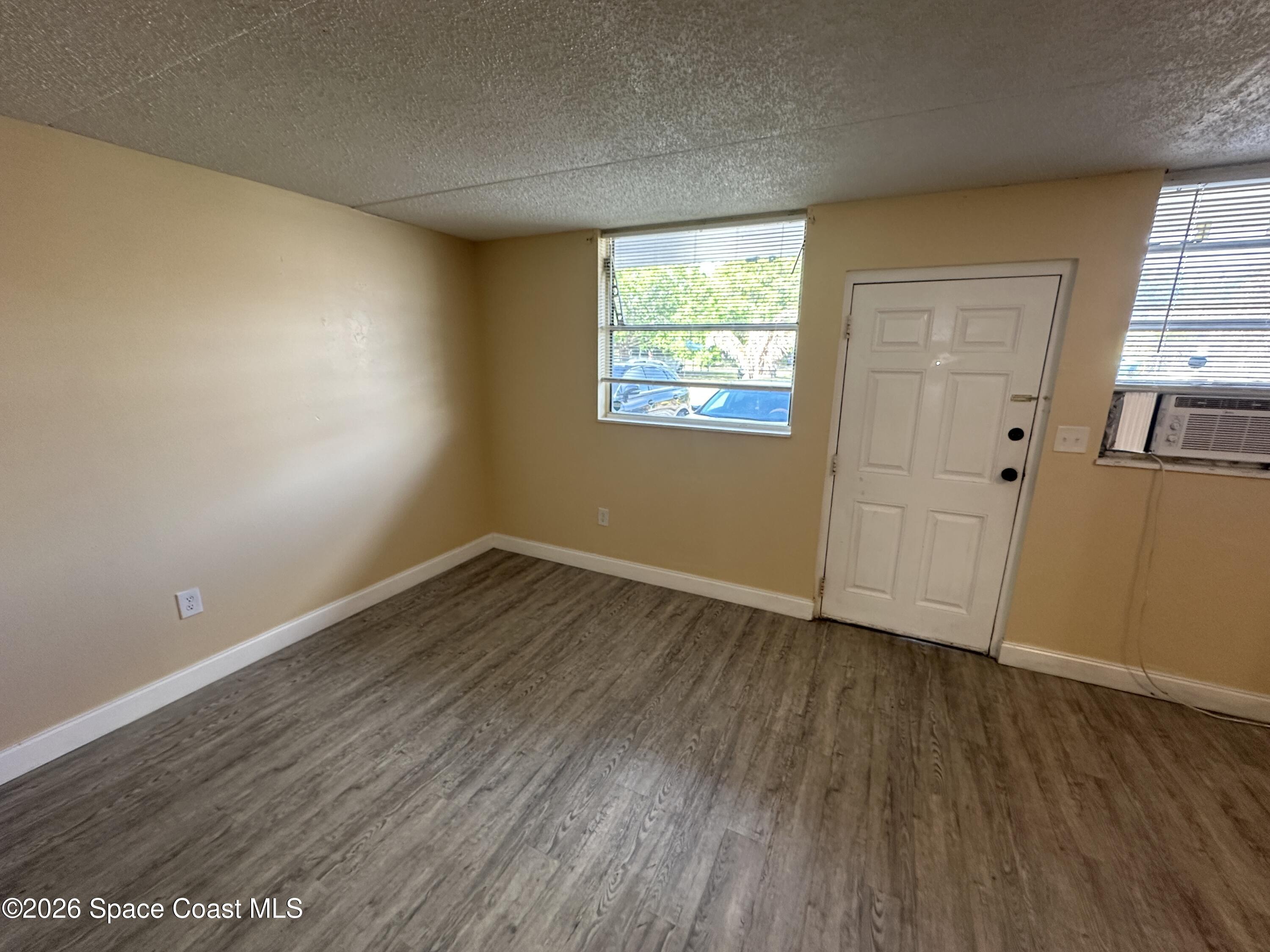 240 Stone Street, Unit 6 Cocoa, FL 32922 - Photo 3 of 7 an empty room with wooden floor and windows
