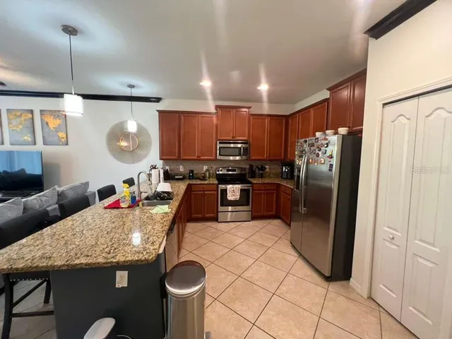 a kitchen with stainless steel appliances granite countertop a refrigerator a stove a sink a dining table and chairs