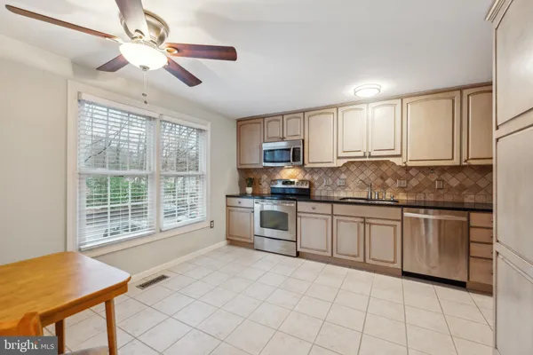 a kitchen with granite countertop a stove a sink a dining table and chairs