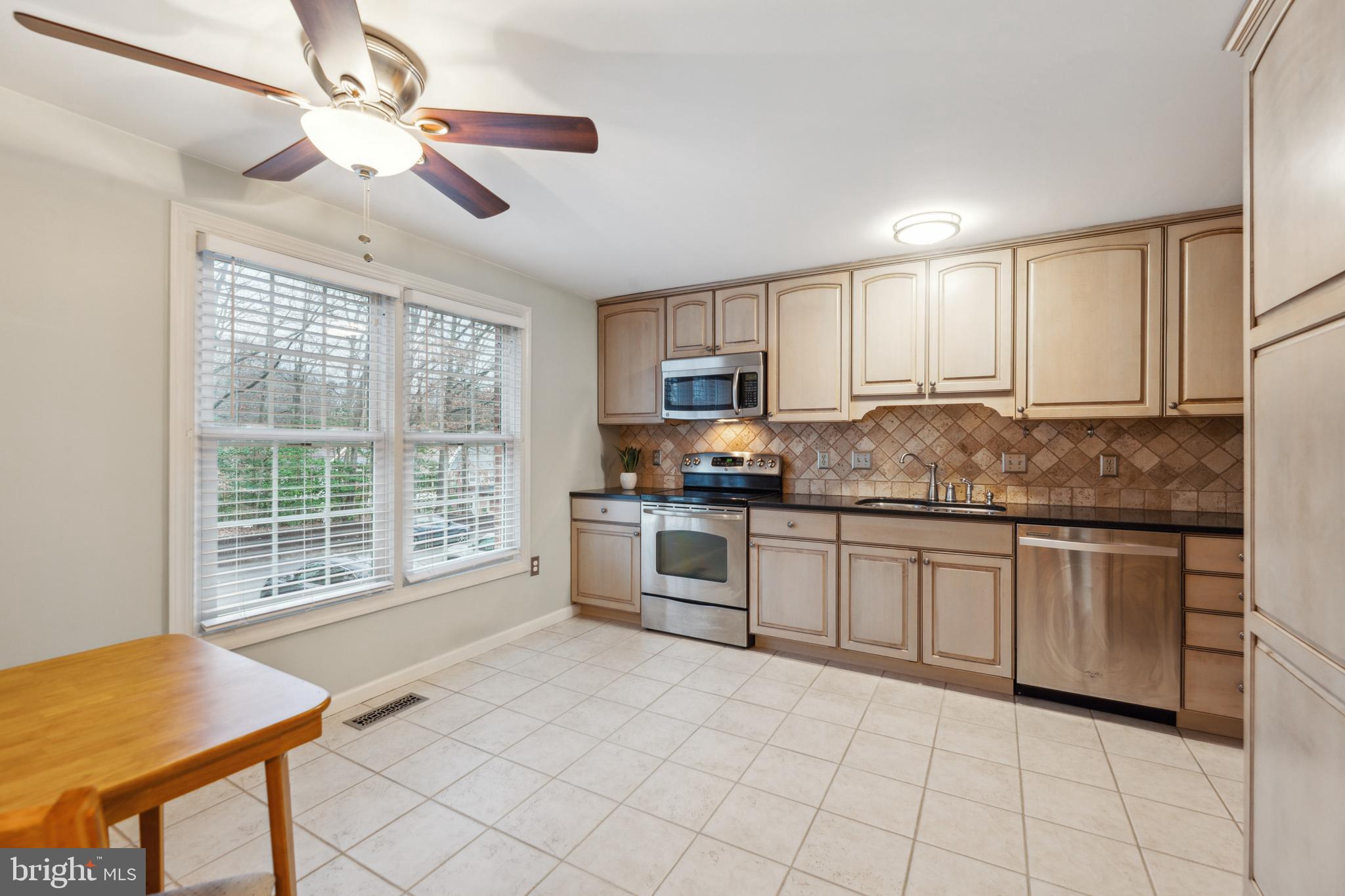 8112 Rhodell Lane Springfield, VA 22153 - Photo 3 of 15 a kitchen with granite countertop a stove a sink a dining table and chairs