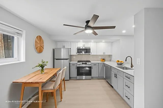 a kitchen with stainless steel appliances granite countertop a dining table and chairs