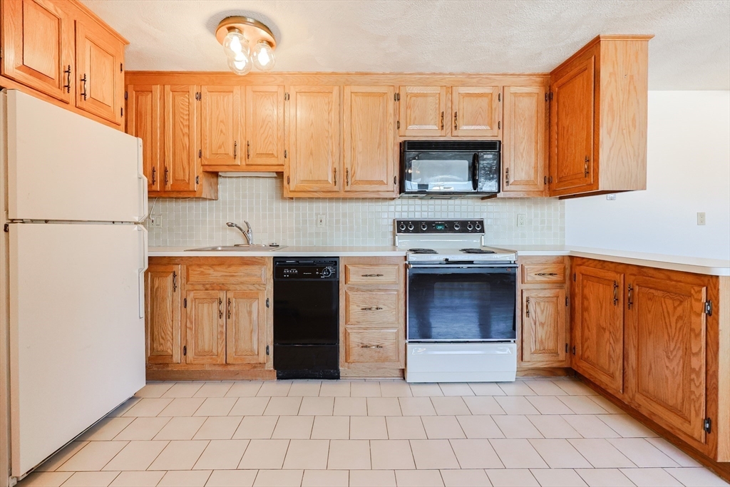 224 School Street, Unit 9 Walpole, MA 02081 - Photo 3 of 31 a kitchen with stainless steel appliances granite countertop a stove a sink and a refrigerator