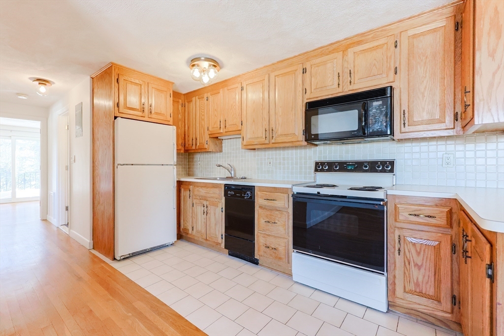 224 School Street, Unit 9 Walpole, MA 02081 - Photo 5 of 31 a kitchen with stainless steel appliances granite countertop a stove a refrigerator and a microwave