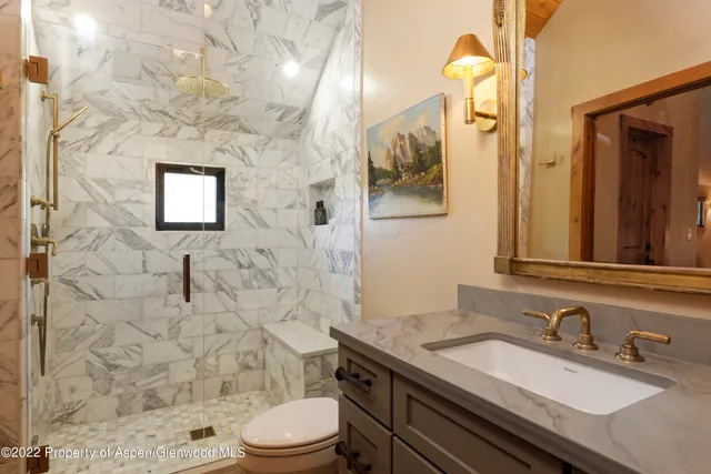 a bathroom with a granite countertop toilet sink and mirror