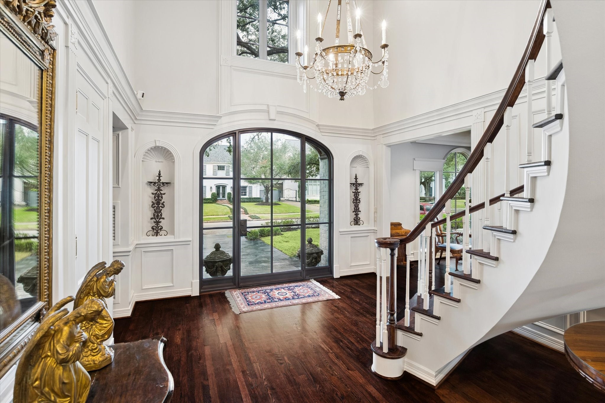 2249 Pelham Drive Houston, TX 77019 - Photo 13 of 50 Sunlit entry framed by arched doors, classic millwork, and a sweeping staircase, offering a graceful transition between the home’s formal and living spaces.