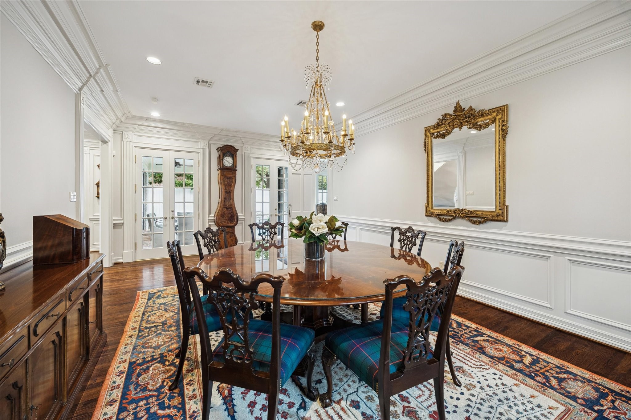 2249 Pelham Drive Houston, TX 77019 - Photo 18 of 50 French doors bring natural light into this formal dining space, highlighting the ornate chandelier, rich hardwood floors, and timeless architectural details.