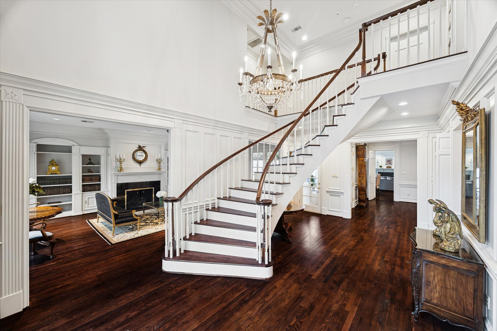 2249 Pelham Drive Houston, TX 77019 - Photo 3 of 50 A grand entry showcasing a sweeping curved staircase, soaring ceilings, and an elegant crystal chandelier, setting a dramatic and timeless first impression.