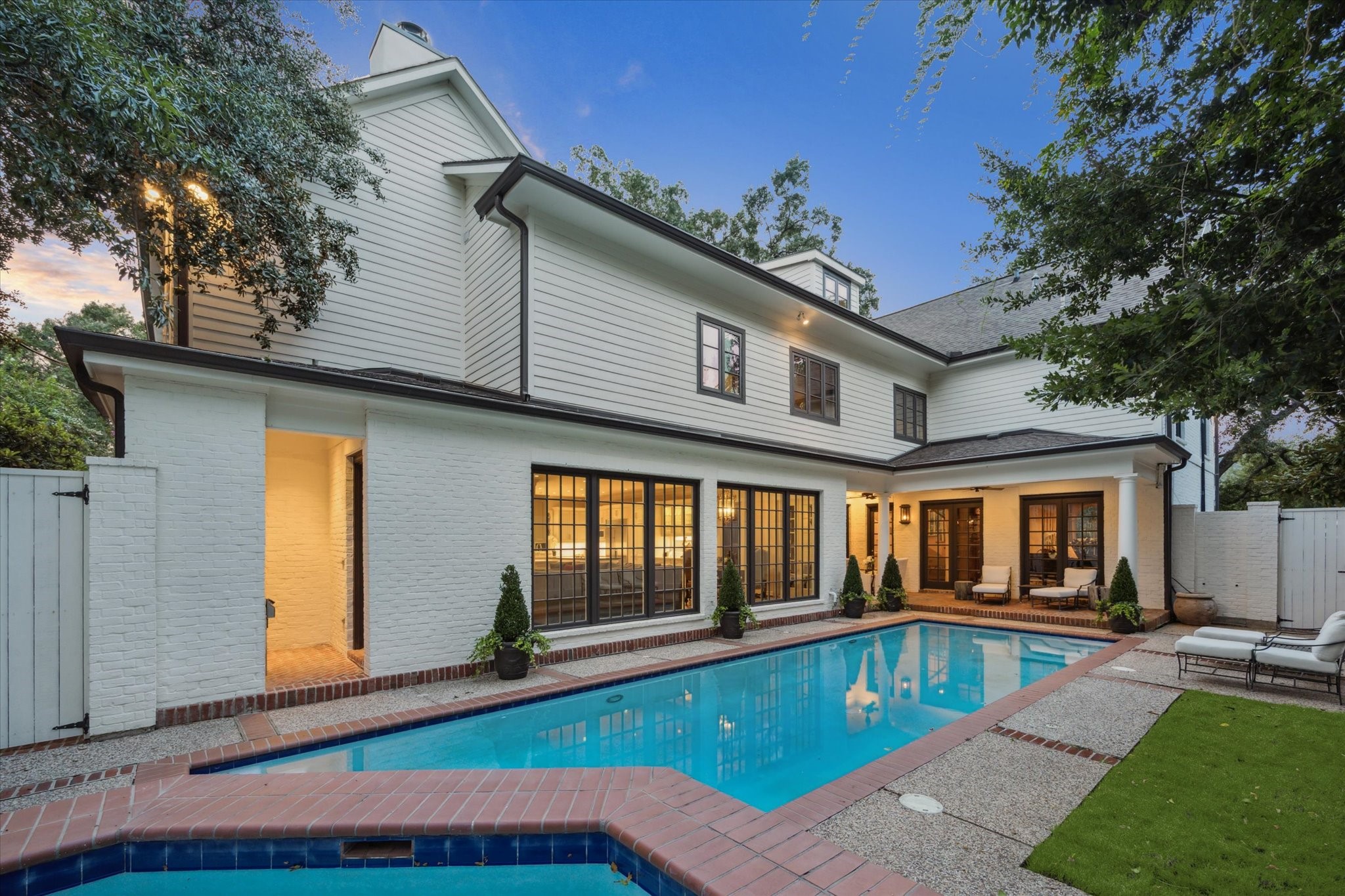 2249 Pelham Drive Houston, TX 77019 - Photo 46 of 50 A view of the inviting backyard oasis, where the pool and spa meet the home’s striking façade of painted brick and expansive windows.