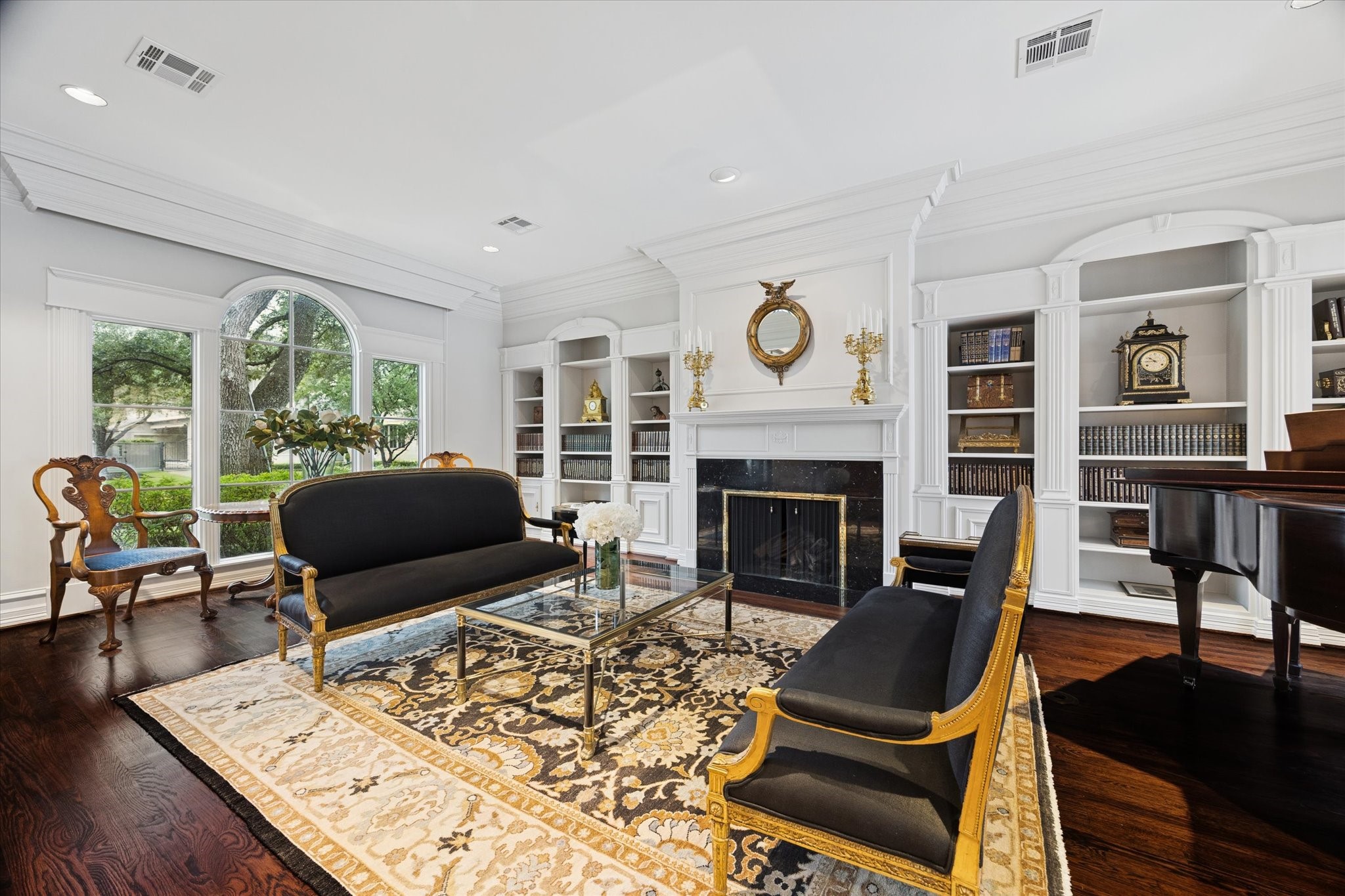 2249 Pelham Drive Houston, TX 77019 - Photo 5 of 50 Refined living room with arched windows, custom built-ins, and a classic fireplace, creating an inviting setting for both formal gatherings and quiet moments.