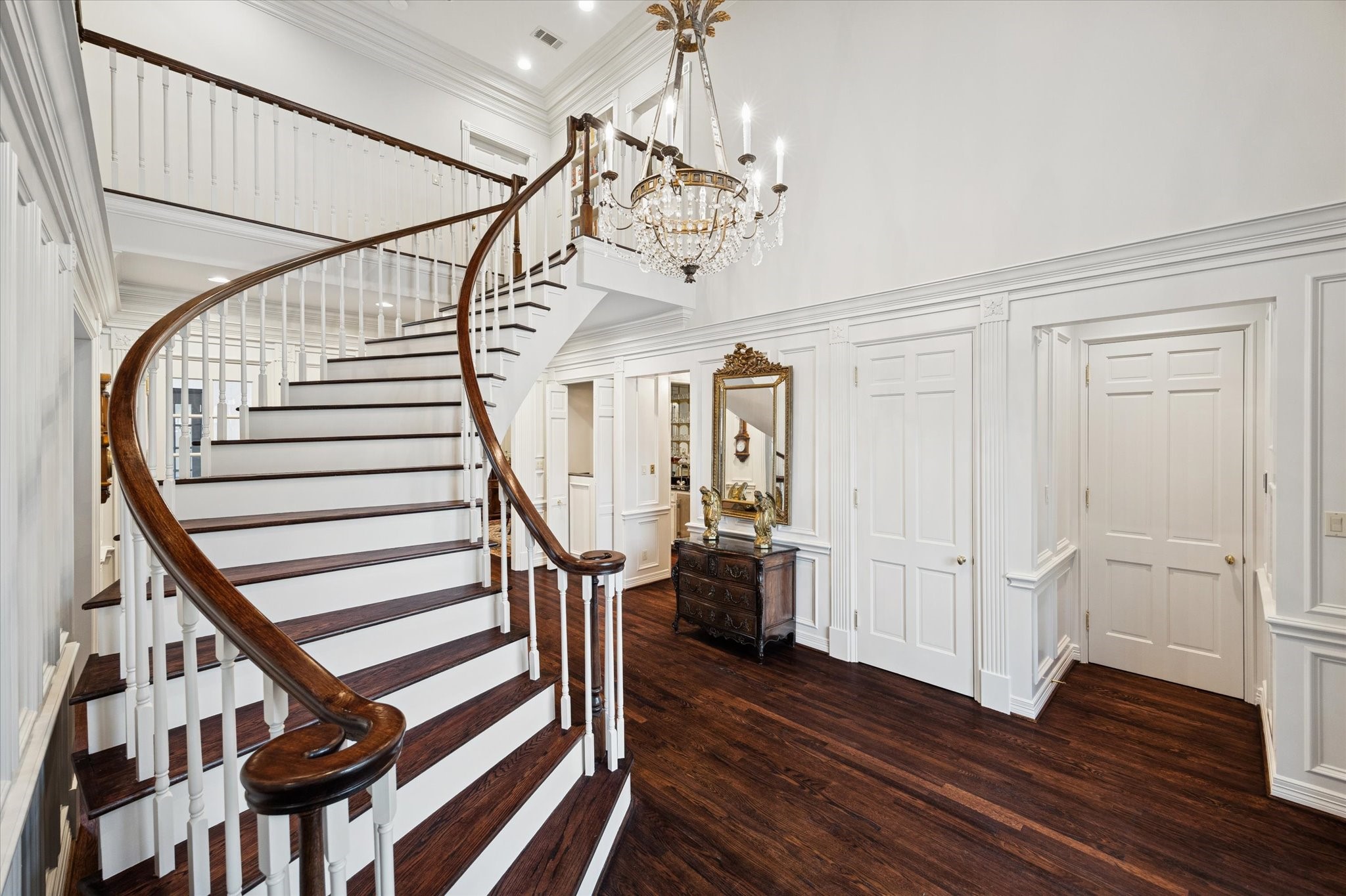 2249 Pelham Drive Houston, TX 77019 - Photo 7 of 50 Elegant double-height foyer sets the tone for the home with a sweeping curved staircase, rich hardwood floors, and a striking crystal chandelier overhead.