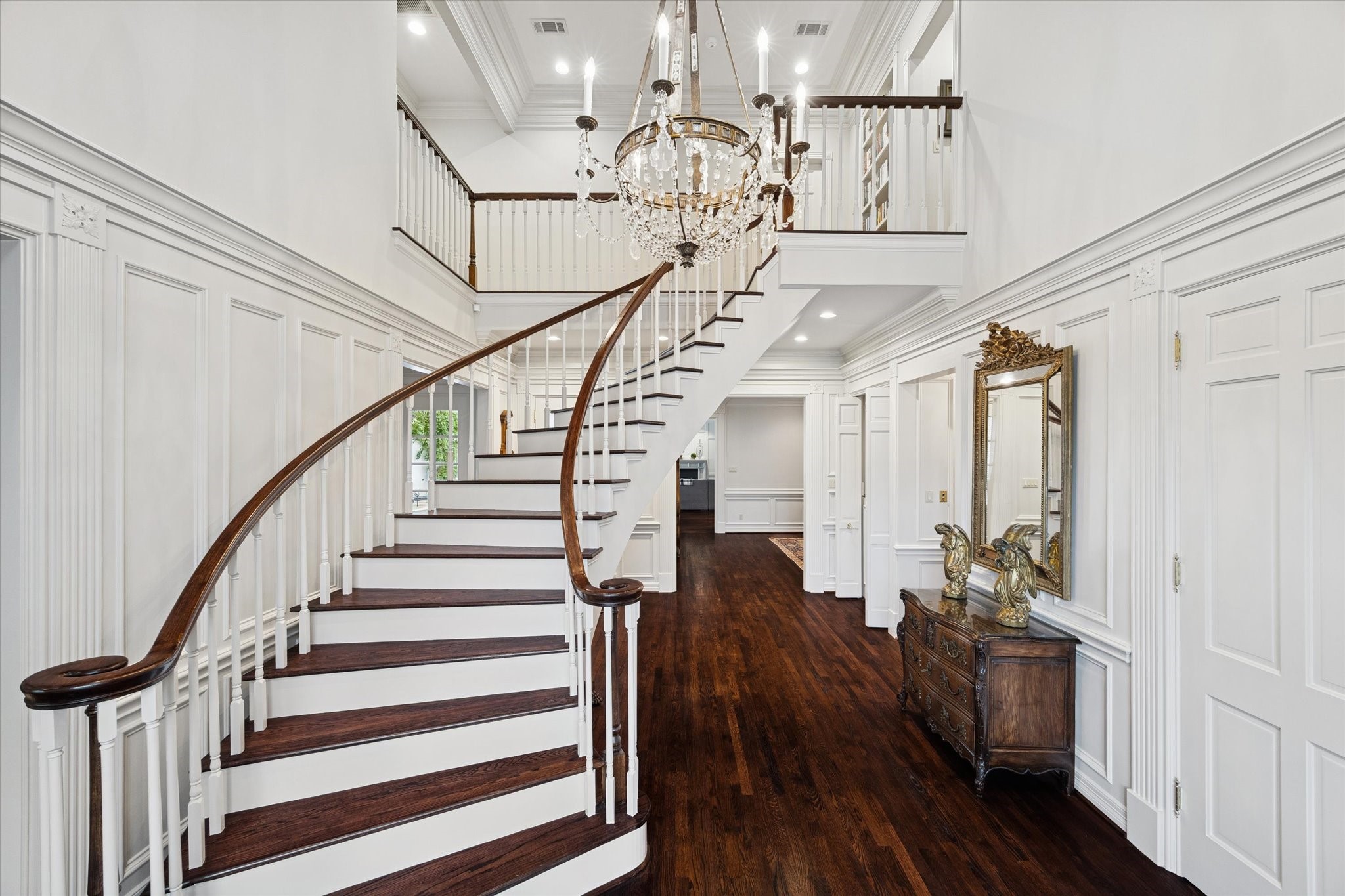 2249 Pelham Drive Houston, TX 77019 - Photo 8 of 50 Architectural centerpiece featuring a sweeping curved staircase, soaring ceilings, and a sparkling chandelier, creating a striking sense of arrival and refined elegance.