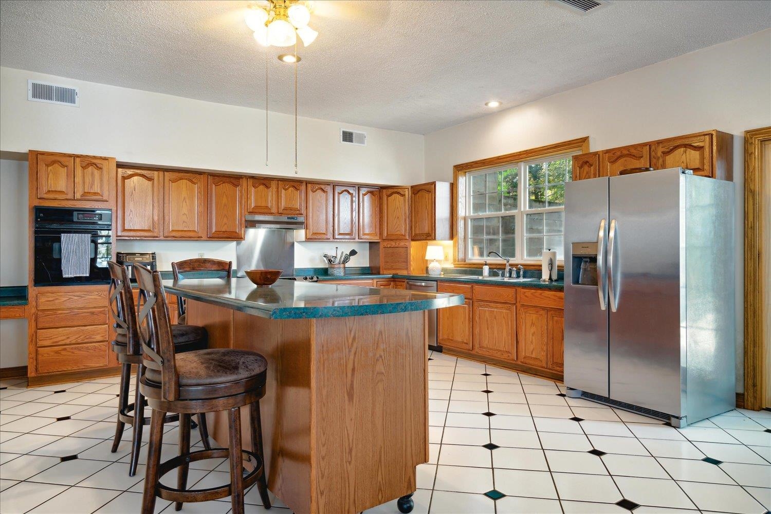997 Vickers Road Big Sandy, TN 38221 - Photo 11 of 40 a kitchen with granite countertop a refrigerator a stove a sink and a dining table with cabinets