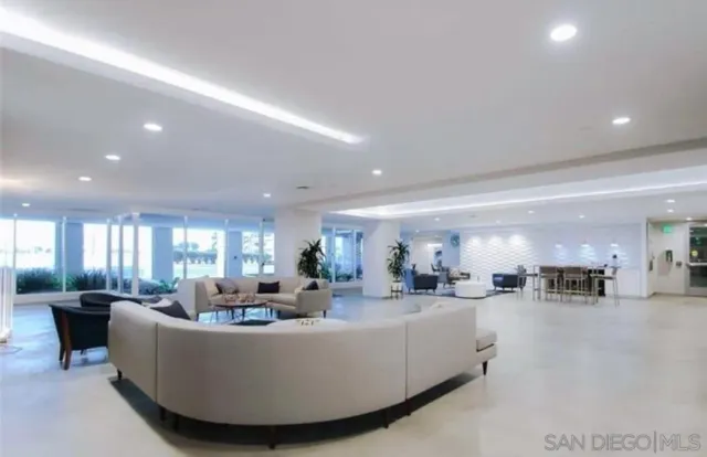 a living room with furniture kitchen area and a large window