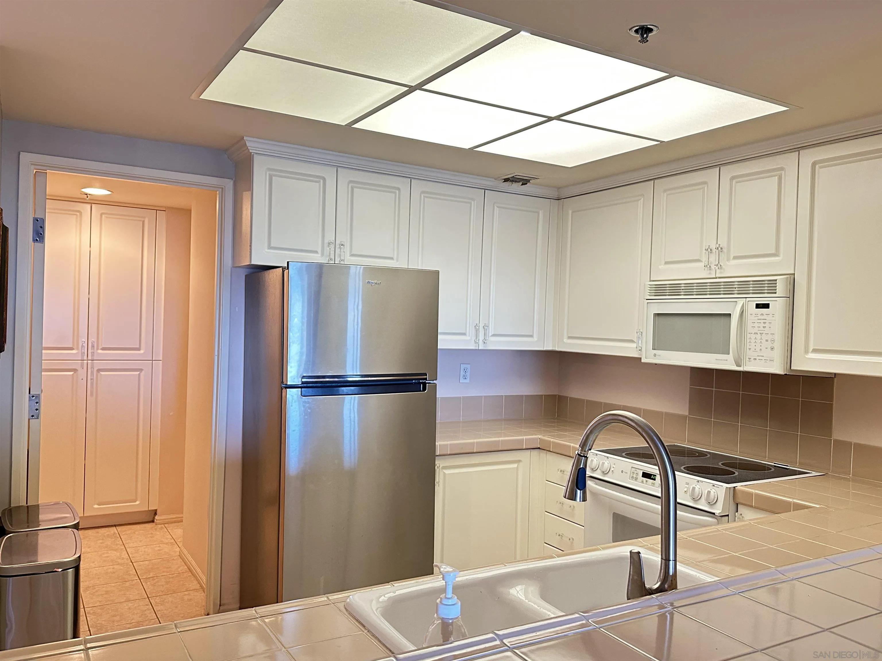 525 East Seaside Way, Unit 1607 Long Beach, CA 90802 - Photo 5 of 41 a kitchen with stainless steel appliances granite countertop a refrigerator a stove a sink and white cabinets with wooden floor