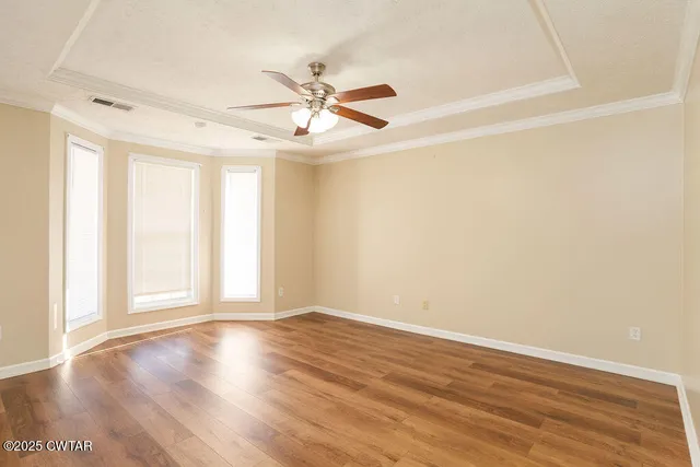 an empty room with wooden floor fan and windows
