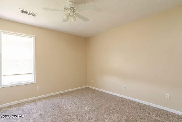 an empty room with a window and a fan