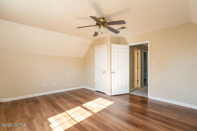 a view of a room with wooden floor a ceiling fan and window