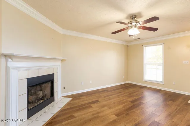 a view of an empty room with wooden floor and a fireplace