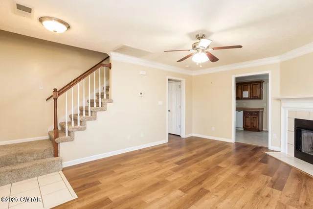 a view of an empty room with wooden floor and a fireplace