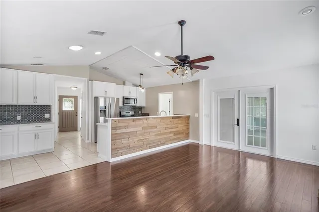 a view of an empty room with a window and wooden floor