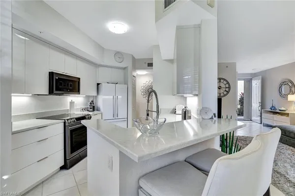 a large white kitchen with a stove a sink a couch dining table and chairs