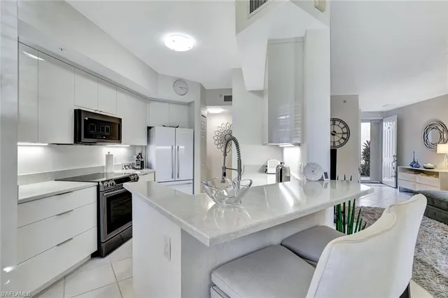 a large white kitchen with a stove a sink a couch dining table and chairs