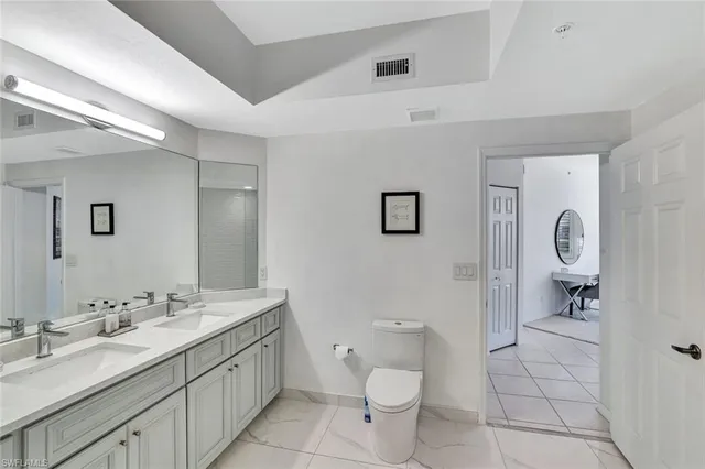 a spacious bathroom with a toilet sink a mirror and vanity
