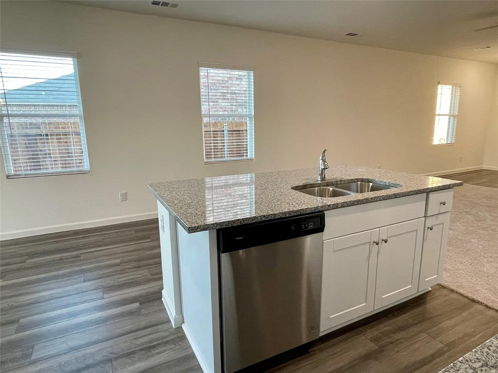 6222 Old Bridge Way Forney, TX 75126 - Photo 6 of 17 a kitchen with granite countertop white cabinets and a wooden floor