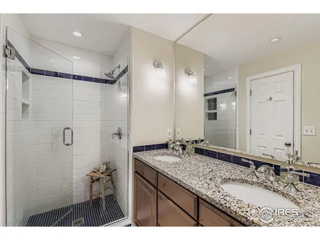 a bathroom with a granite countertop sink a mirror and a shower