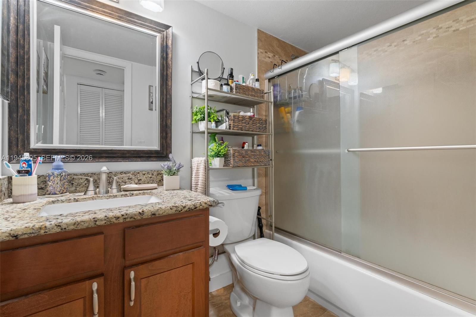 10005 Winding Lake Road, Unit 106 Sunrise, FL 33351 - Photo 23 of 41 a bathroom with a granite countertop sink toilet and shower