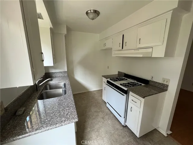 a kitchen with granite countertop a sink stove and cabinets