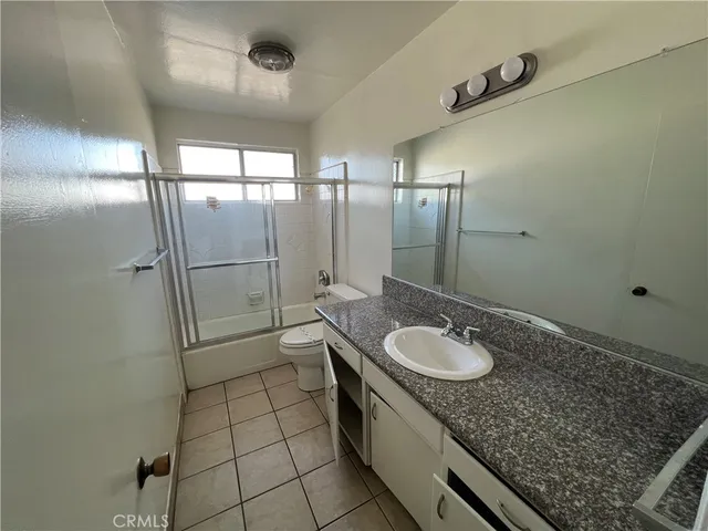 a bathroom with a granite countertop sink a toilet and shower